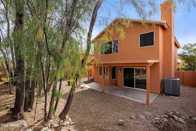 rear view of house featuring central air condition unit, stucco siding, a patio area, fence, and a chimney