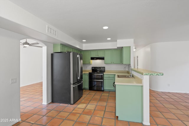 kitchen featuring green cabinets, freestanding refrigerator, a sink, and range with two ovens