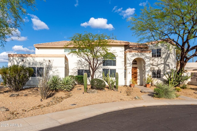 mediterranean / spanish home featuring stucco siding and a tiled roof
