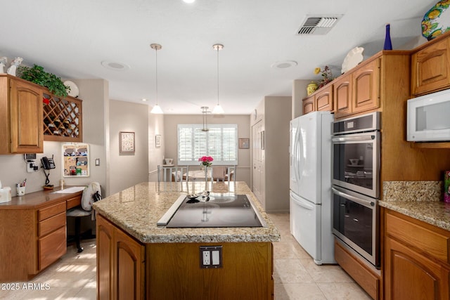 kitchen with white appliances, a kitchen island, brown cabinetry, and hanging light fixtures