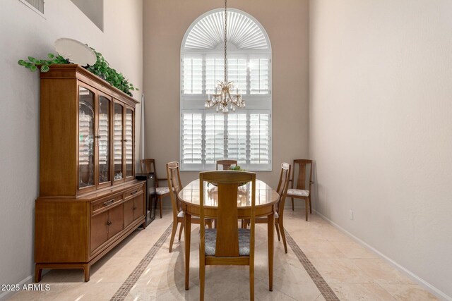 dining room featuring inlaid floor details, a chandelier, and baseboards