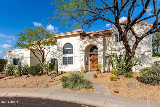 mediterranean / spanish home featuring a tile roof and stucco siding