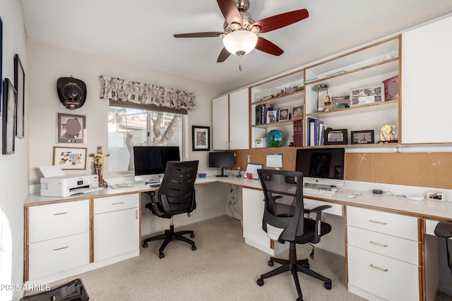 office featuring built in desk, light colored carpet, and a ceiling fan