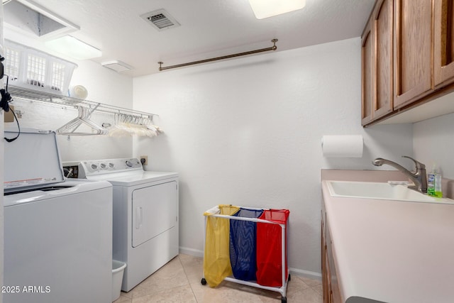 clothes washing area with independent washer and dryer, cabinet space, light tile patterned flooring, and baseboards
