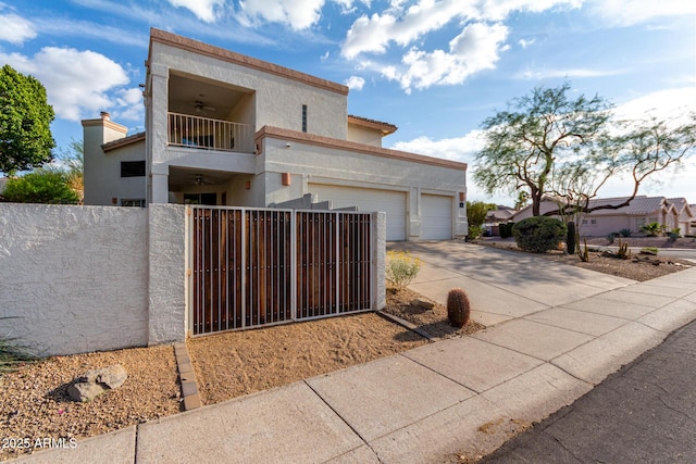 view of front of property with a balcony, a ceiling fan, a fenced front yard, driveway, and stucco siding