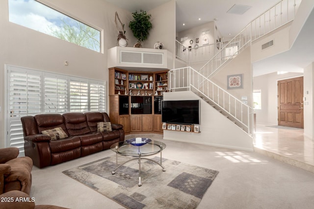 living room with a towering ceiling, carpet flooring, and stairs