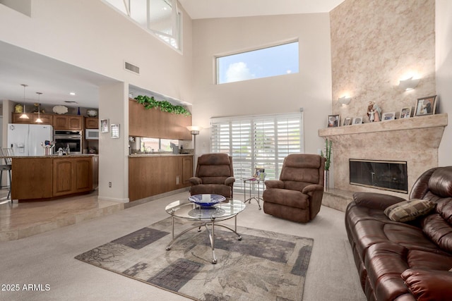 living room featuring light carpet, a high end fireplace, a towering ceiling, and healthy amount of natural light