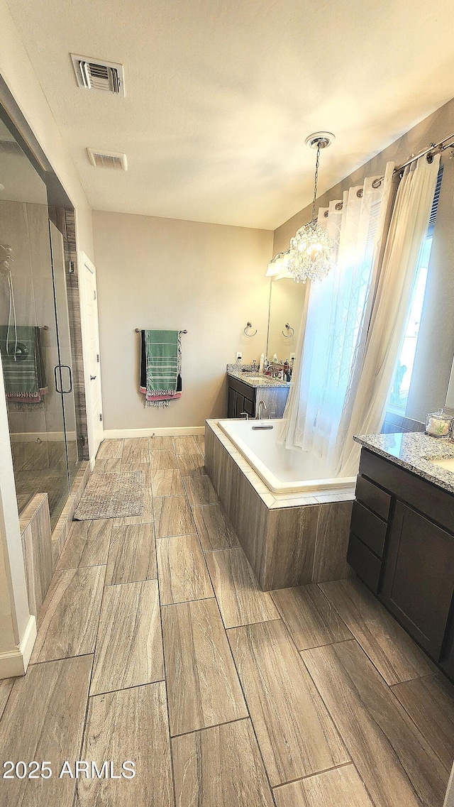 bathroom with vanity, an inviting chandelier, and plus walk in shower