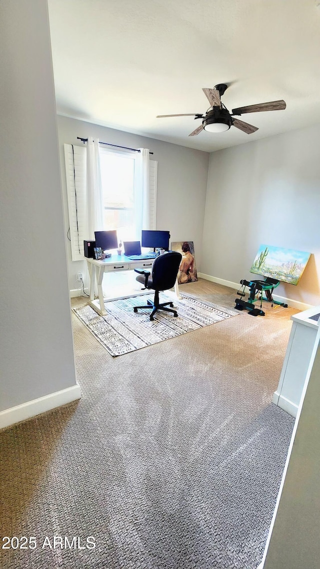 carpeted home office featuring ceiling fan