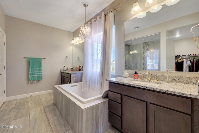 bathroom with tiled bath, vanity, and a chandelier