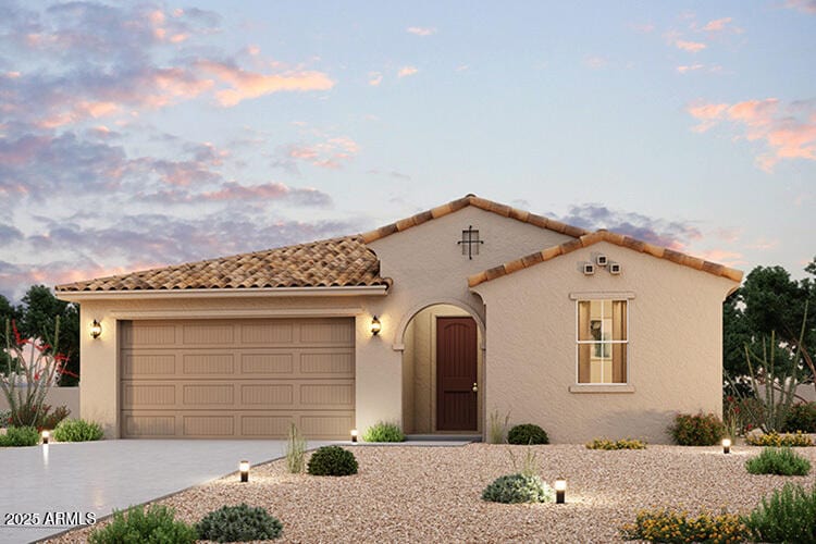 mediterranean / spanish-style home with a tile roof, an attached garage, driveway, and stucco siding