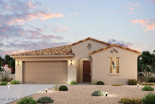 mediterranean / spanish-style home with a tile roof, an attached garage, driveway, and stucco siding