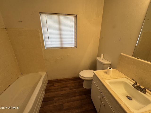 bathroom featuring vanity, toilet, hardwood / wood-style floors, and a washtub