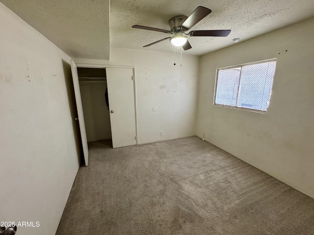 unfurnished bedroom featuring ceiling fan, light colored carpet, a closet, and a textured ceiling