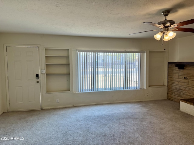 unfurnished living room featuring ceiling fan, carpet, and a textured ceiling