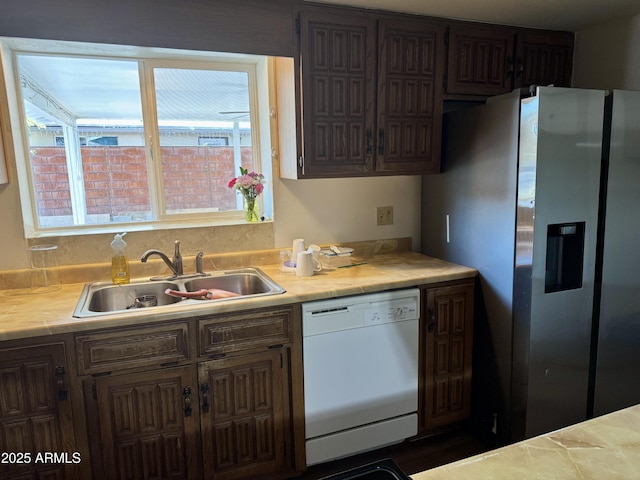 kitchen featuring white dishwasher, sink, and stainless steel refrigerator with ice dispenser