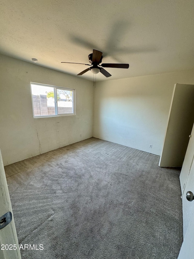 carpeted empty room with ceiling fan and a textured ceiling