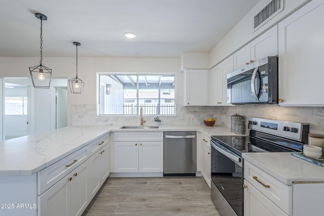 kitchen featuring stainless steel appliances, visible vents, a sink, a peninsula, and white cabinetry