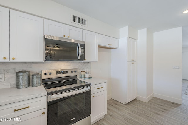 kitchen featuring backsplash, light wood-style floors, appliances with stainless steel finishes, and white cabinets