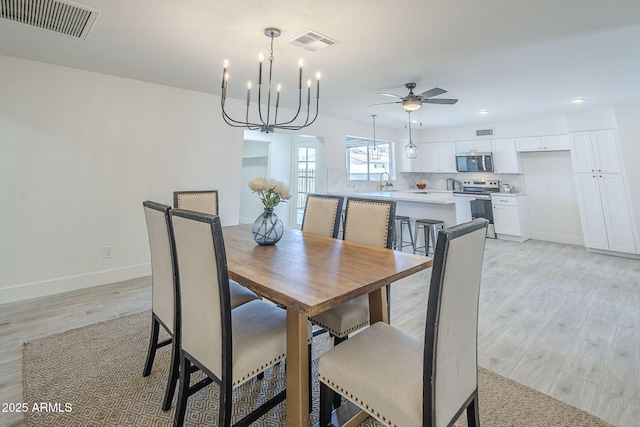 dining area with baseboards, visible vents, and ceiling fan with notable chandelier