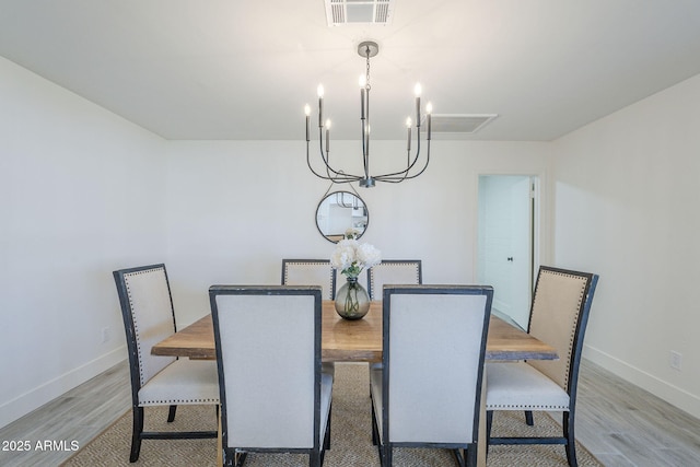 dining area featuring a notable chandelier, baseboards, visible vents, and light wood-style floors