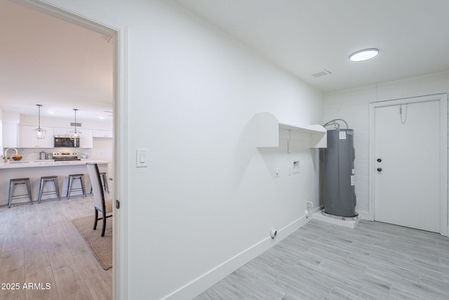 washroom featuring water heater, light wood-style floors, laundry area, and hookup for a washing machine