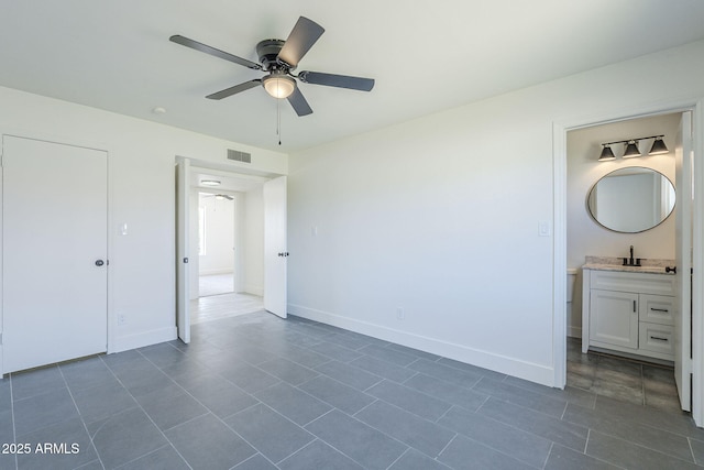 unfurnished bedroom with visible vents, a sink, dark tile patterned floors, ensuite bath, and baseboards