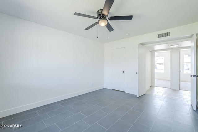 unfurnished bedroom with baseboards, dark tile patterned floors, and visible vents