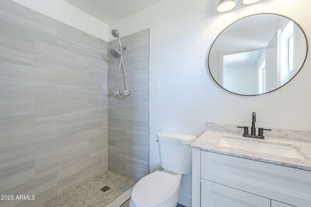 full bathroom featuring toilet, vanity, and tiled shower