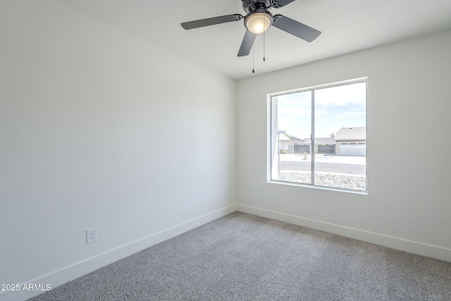empty room with light colored carpet, baseboards, and a ceiling fan
