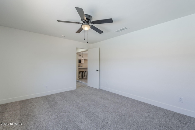 empty room featuring baseboards, visible vents, carpet, and ceiling fan