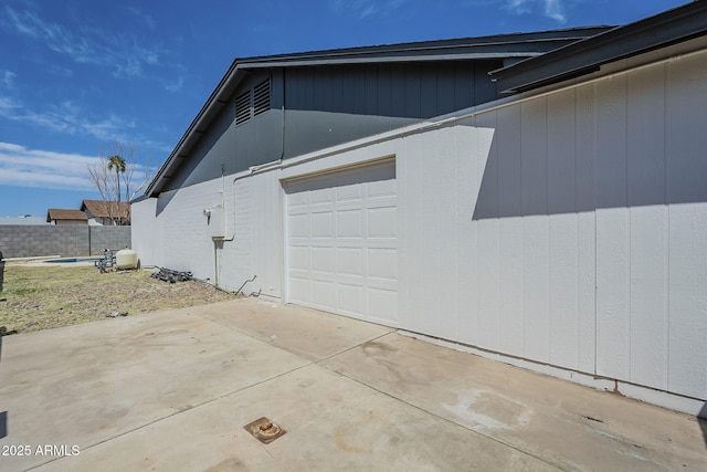 view of side of home with fence, driveway, and a garage