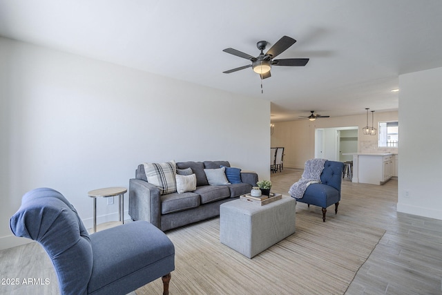 living room featuring light wood-type flooring, baseboards, and ceiling fan