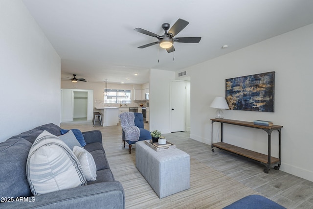 living area featuring ceiling fan, baseboards, light wood-style floors, and visible vents