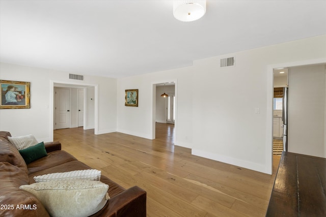 living room with light wood-type flooring, baseboards, and visible vents