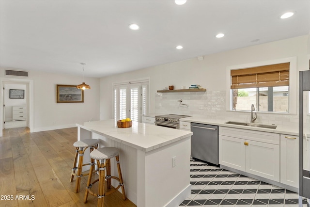 kitchen featuring a center island, backsplash, visible vents, stainless steel appliances, and a sink