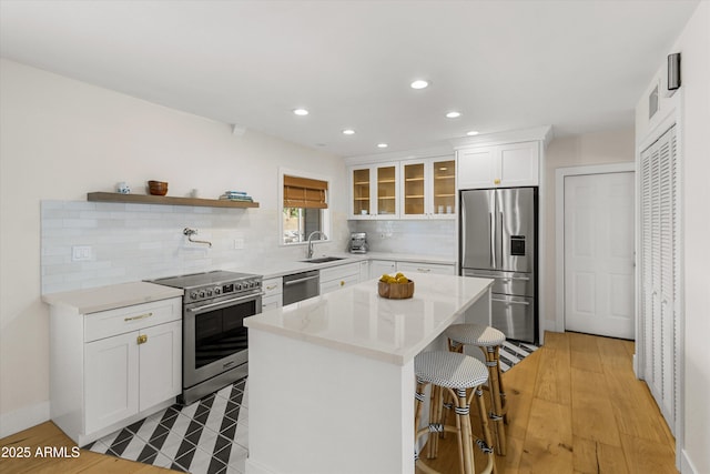 kitchen featuring a kitchen bar, tasteful backsplash, recessed lighting, appliances with stainless steel finishes, and a sink