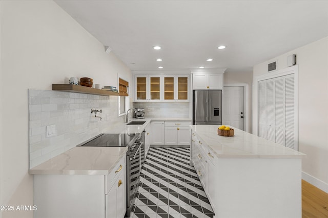 kitchen featuring tasteful backsplash, a center island, visible vents, stainless steel appliances, and a sink