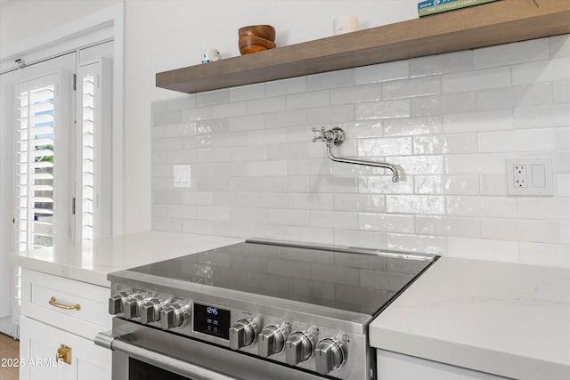kitchen featuring open shelves, white cabinetry, stainless steel electric stove, and backsplash