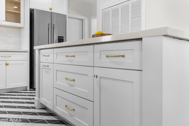room details with stainless steel fridge with ice dispenser, glass insert cabinets, white cabinets, light countertops, and decorative backsplash