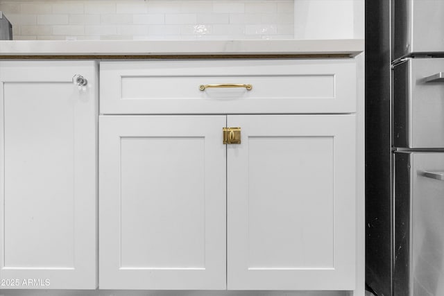 details featuring white cabinets and freestanding refrigerator