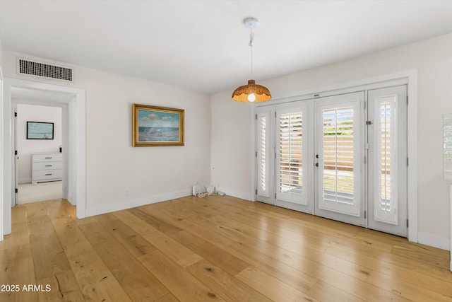 unfurnished dining area with light wood-type flooring, french doors, baseboards, and visible vents
