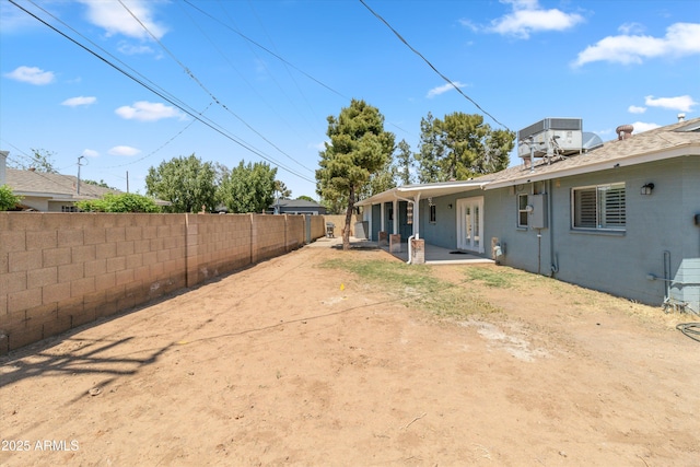 view of yard with central air condition unit, french doors, and fence