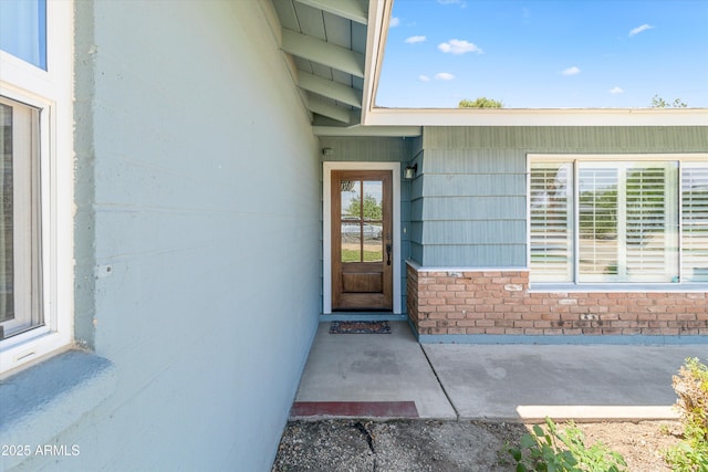view of exterior entry featuring brick siding