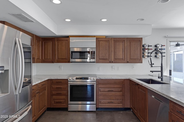 kitchen with appliances with stainless steel finishes, sink, and light stone counters