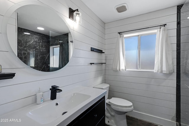 bathroom with toilet, vanity, and wooden walls