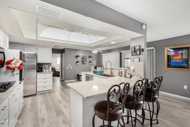 kitchen with sink, light hardwood / wood-style flooring, a breakfast bar, appliances with stainless steel finishes, and white cabinets