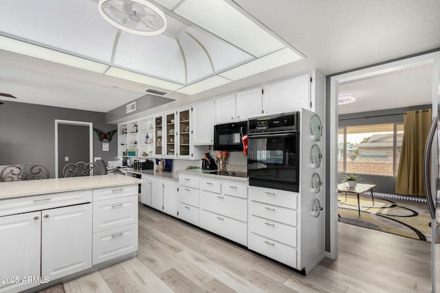 kitchen with white cabinetry, ceiling fan, light hardwood / wood-style floors, and black appliances