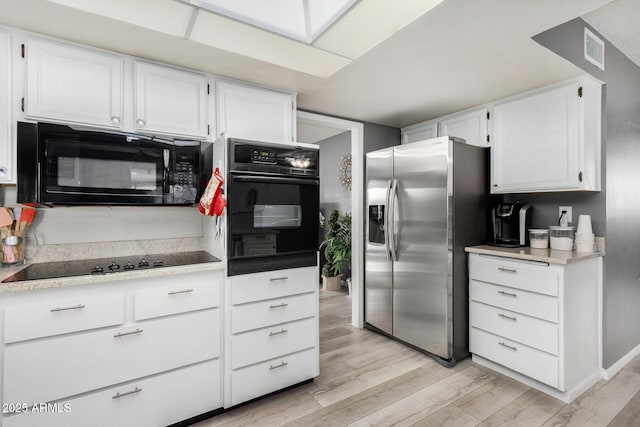 kitchen featuring white cabinetry, light hardwood / wood-style flooring, and black appliances