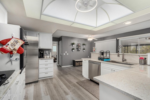 kitchen with sink, light wood-type flooring, ceiling fan, stainless steel appliances, and white cabinets